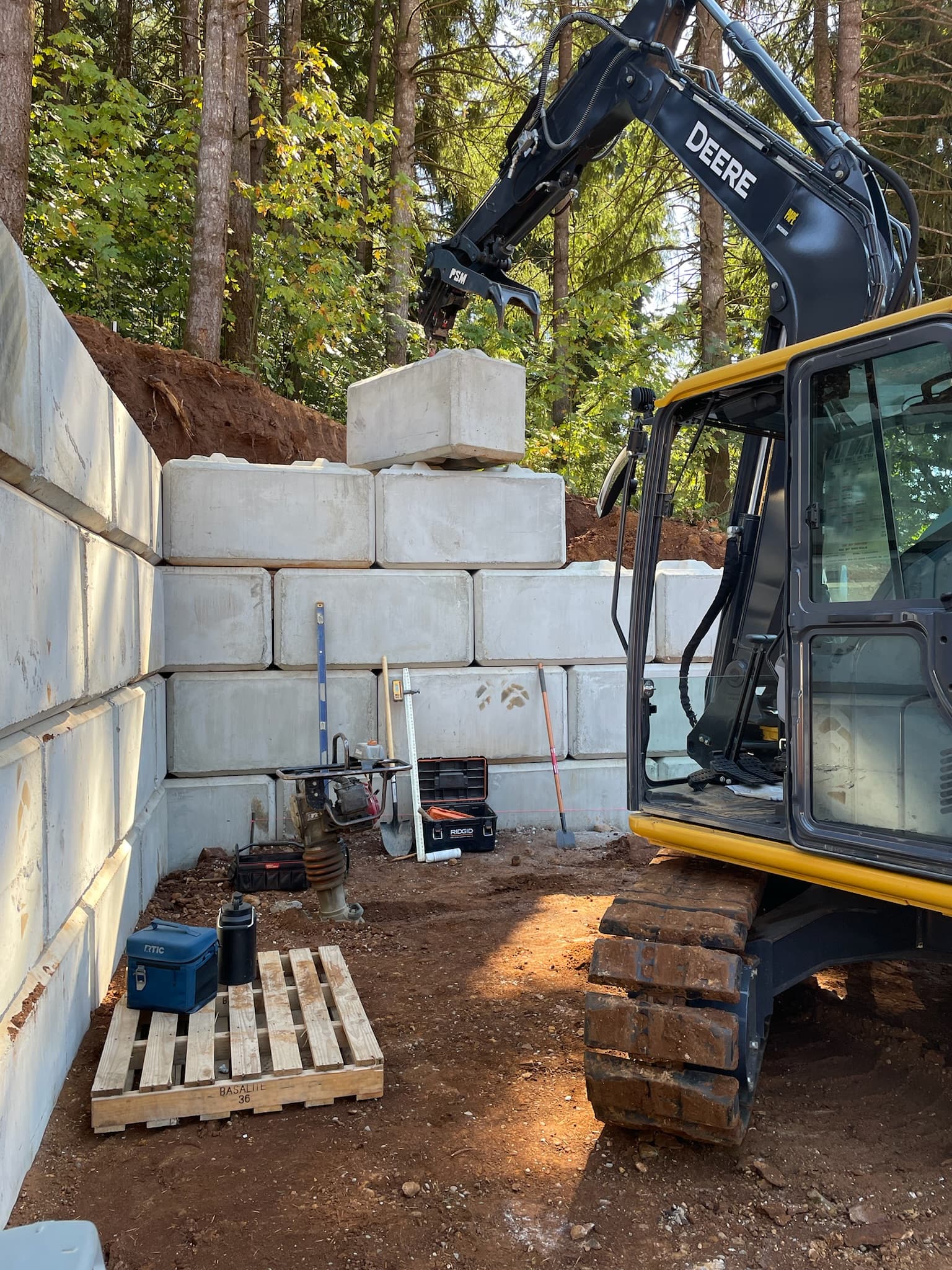 John Deere excavator setting a large Ultra Block onto the terraced wall on a commercial development site in Salem, Oregon
